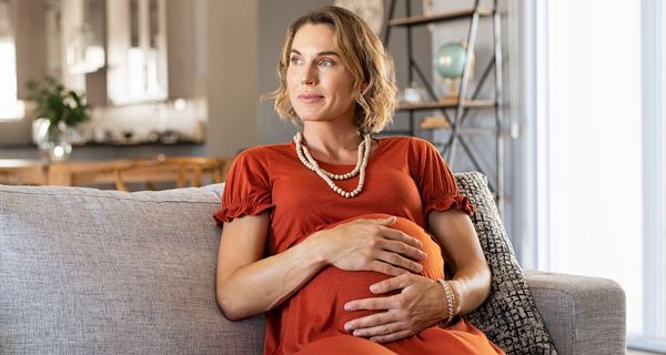 Schwangere Frau sitzt auf dem Sofa.