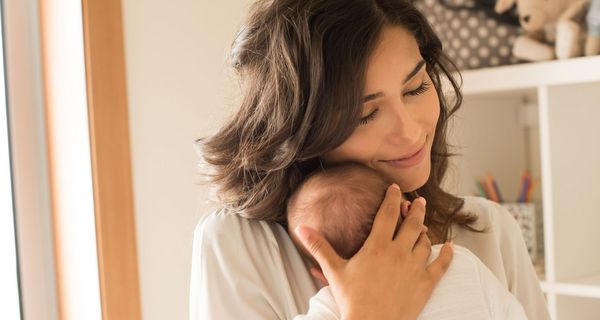 Frau kuschelt mit einem neugeborenen Baby.