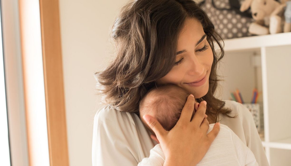 Frau kuschelt mit einem neugeborenen Baby.