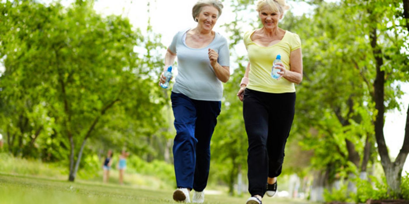 Zwei fröhliche Frauen ca. Mitte 50 beim Joggen im Park