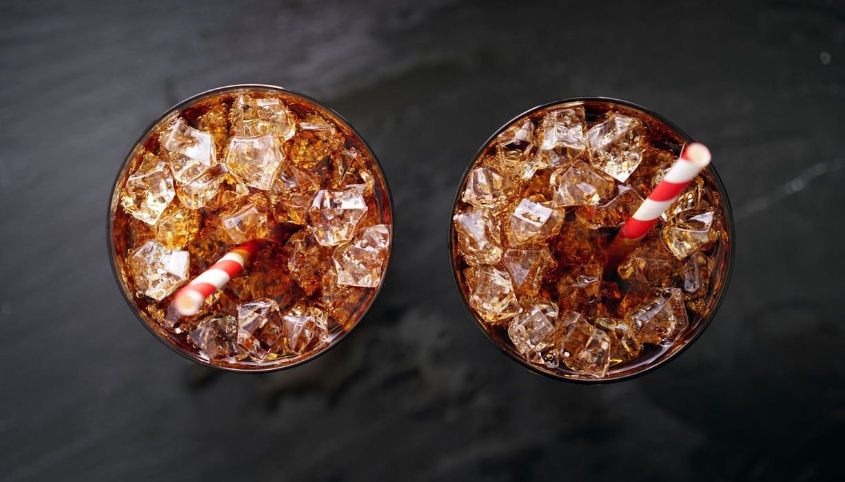 Zwei Gläser mit Cola und Eis auf dunklem Hintergrund.