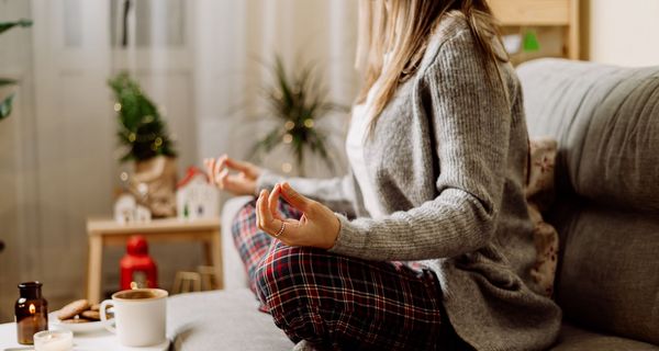 Frau, sitzt auf der Couch und meditiert.