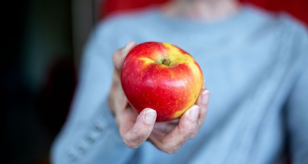 Frau hält einen Apfel in der Hand. 