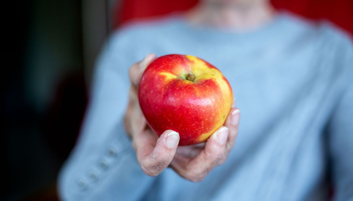 Frau hält einen Apfel in der Hand. 
