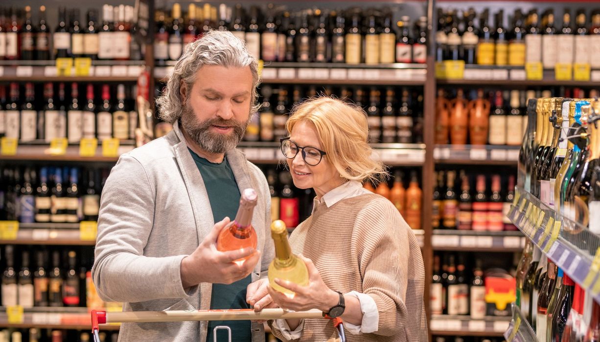 Frau und Mann im Supermarkt vor dem Weinregal