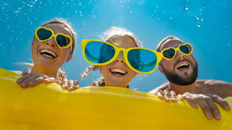Familie mit gelben Sonnenbrillen im Pool.