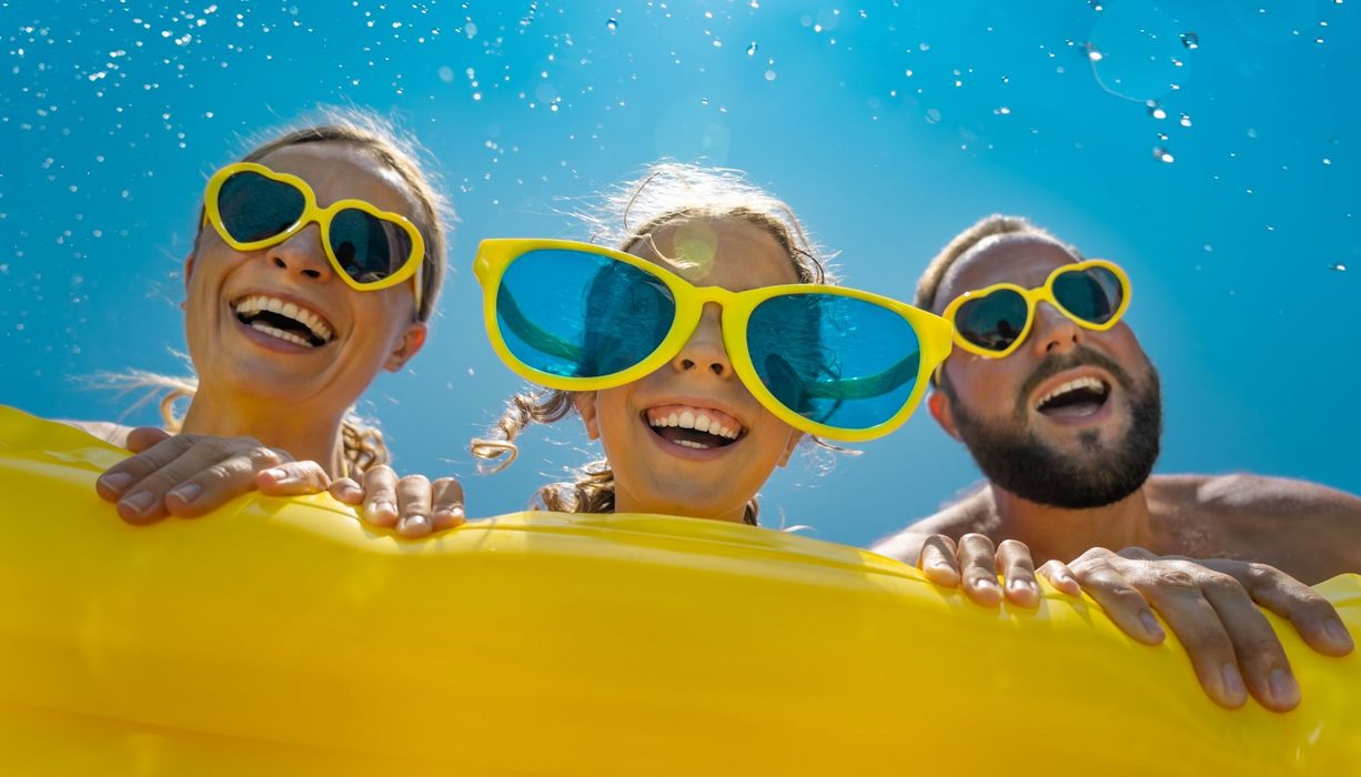 Familie mit gelben Sonnenbrillen im Pool.