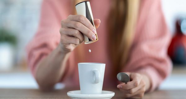 Frau süßt ihren Kaffee mit Süßstoff.