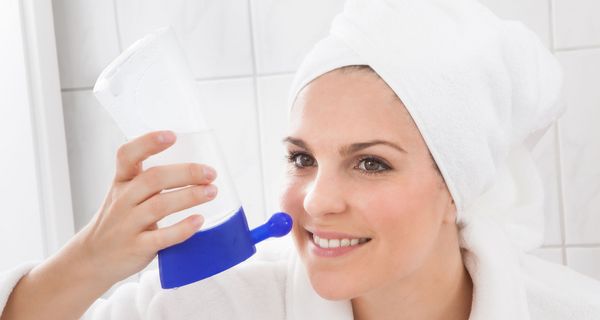 Frau mit Handtuchturban nutzt Nasendusche.