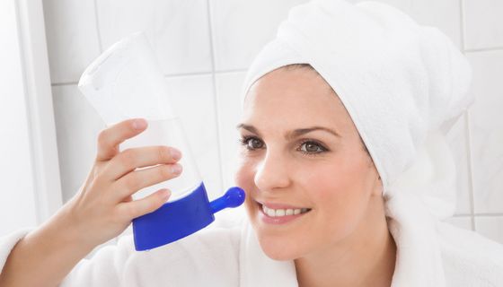 Frau mit Handtuchturban nutzt Nasendusche.