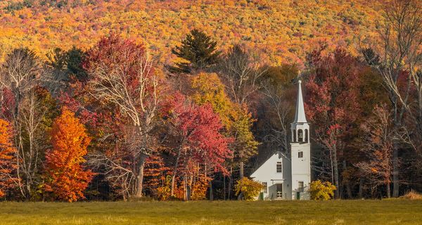 Kirche vor herbstlich gefärbtem Wald