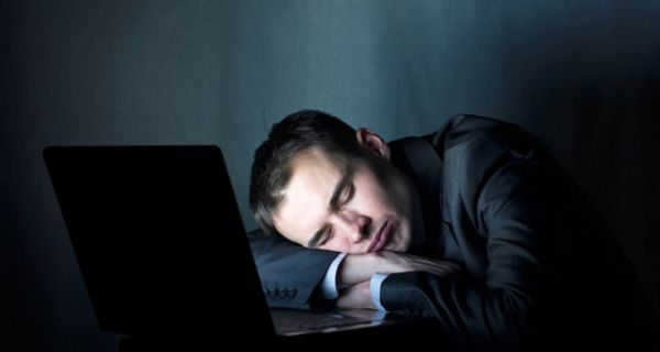 Schlafender Mann vor einem PC