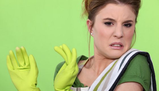 Frau mit Putzhandschuhen und angewidertem Gesichtsausdruck.