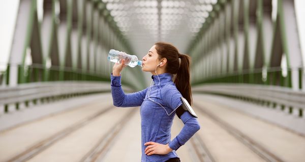 Sportlerin trinkt aus Plastikflasche.