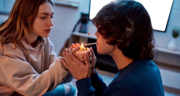 Zwei Jugendliche, Mädchen zündet Jungen einen Joint mit einem Feuerzeug ein.