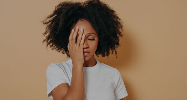 Junge Frau, hält eine Hand an die Seite ihres Gesichts, Augen geschlossen.