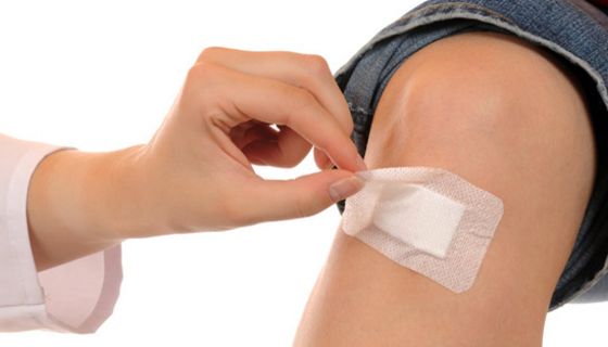 Hand klebt Pflaster auf Kinderknie.