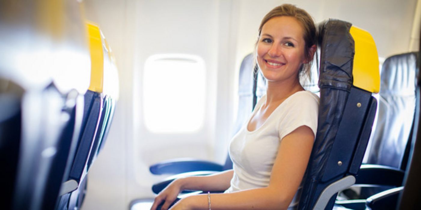 Junge Frau sitzt in einem Flugzeug.