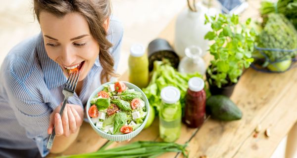 Junge Frau, isst eine Schüssel mi Salat.