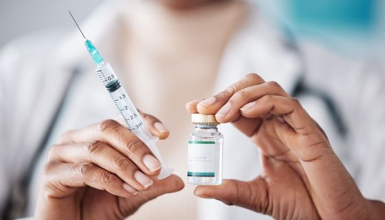 Apothekerin hält eine Impfung und eine Spritze in der Hand. 