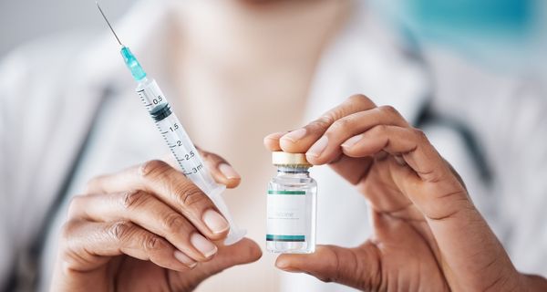Apothekerin hält eine Impfung und eine Spritze in der Hand.
