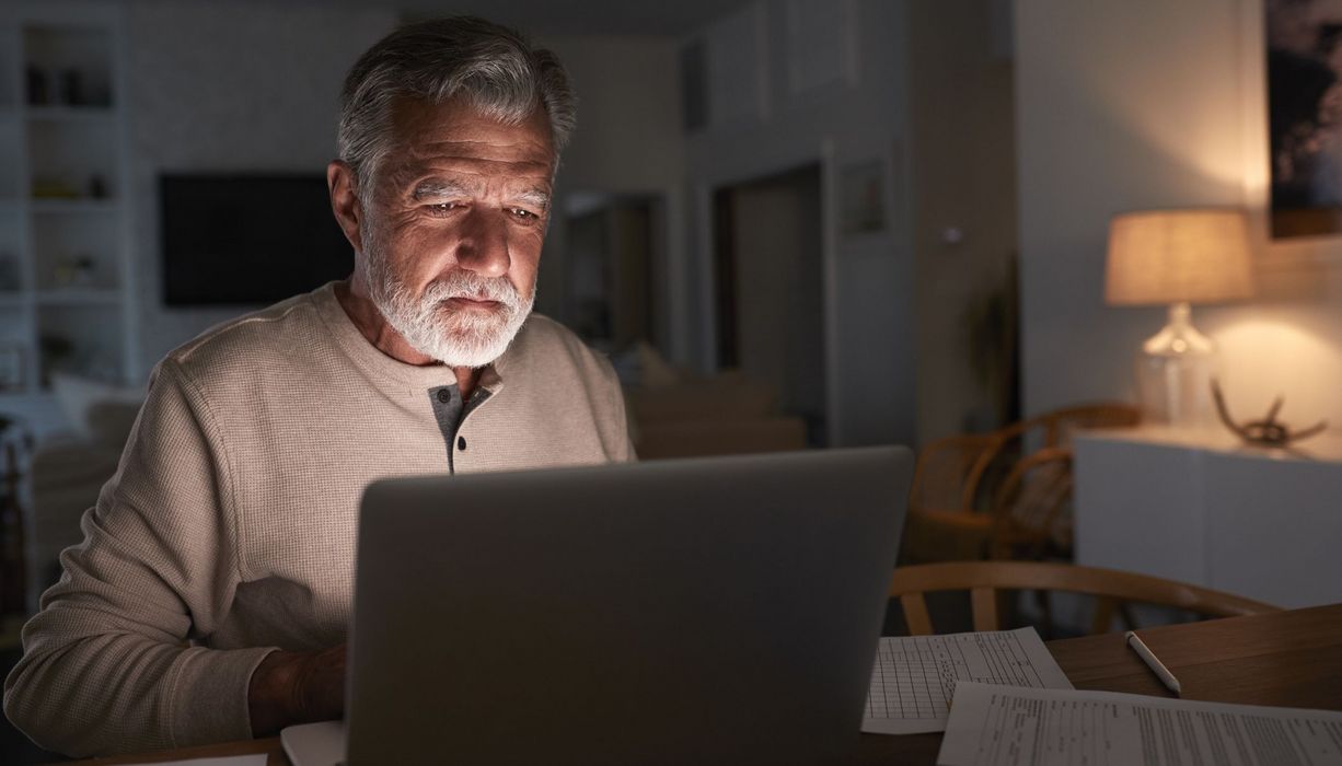 Älterer Mann, sitzt vor dem Laptop.