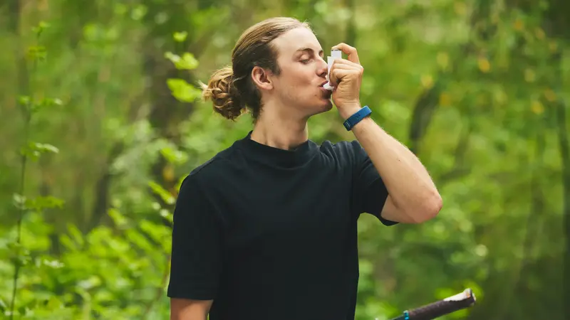 Junger Mann, nutzt Asthmaspray.