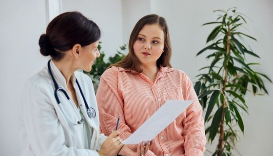 Übergewichtige junge Frau im Gespräch mit Ärztin.