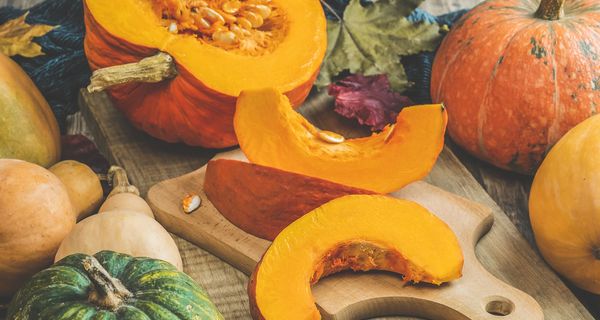 Kürbisspalten liegen auf einem Brett. Darum herum sind andere Kürbisse drapiert.