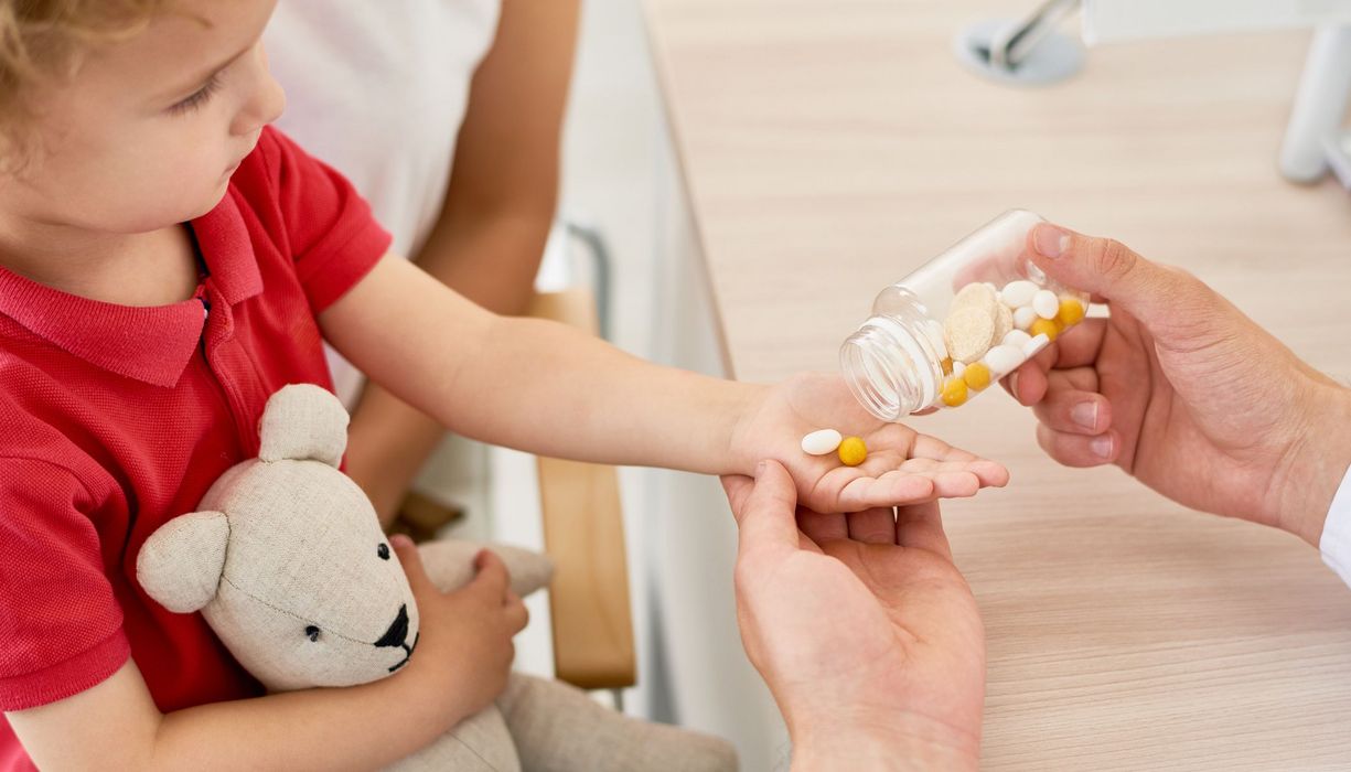 Kleines Kind bekommt Tabletten auf die Hand.