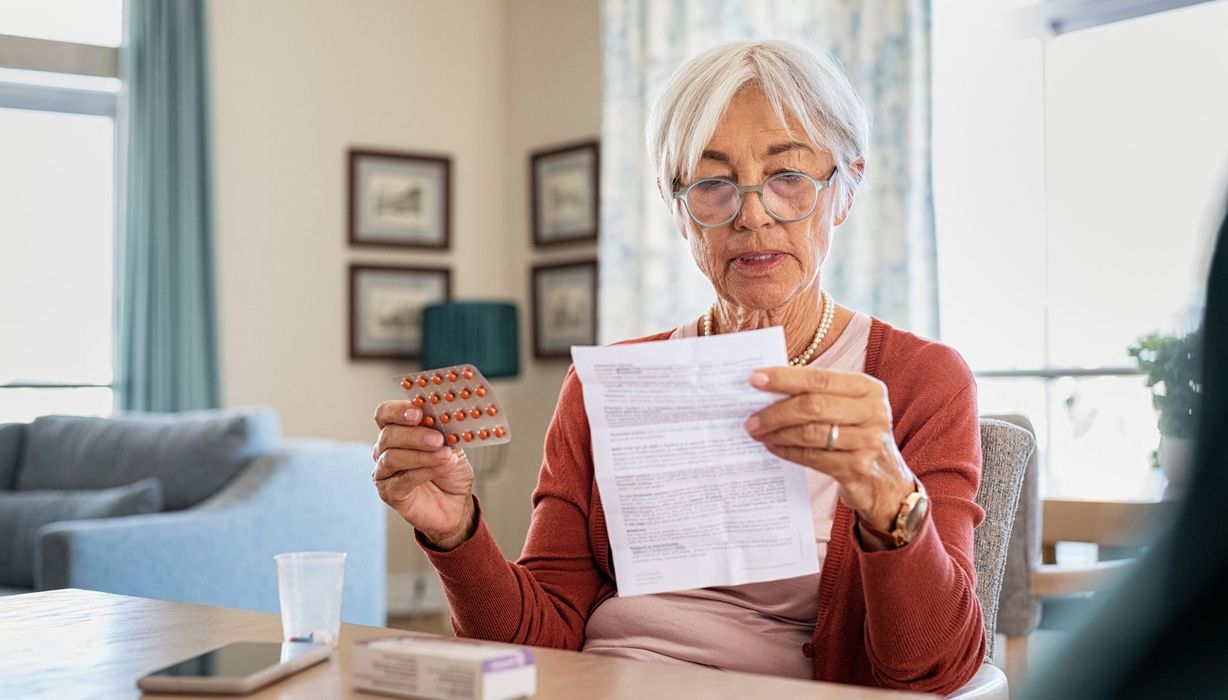 Ältere Frau liest Beipackzettel eines Medikaments.