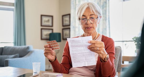 Ältere Frau liest Beipackzettel eines Medikaments.