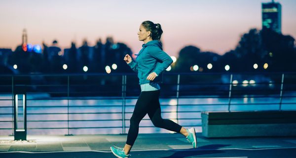 Junge Frau, joggt bei Dunkelheit in der Stadt.