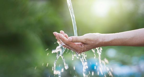 Wasserstrahl, fließt auf eine ausgestreckte Hand.