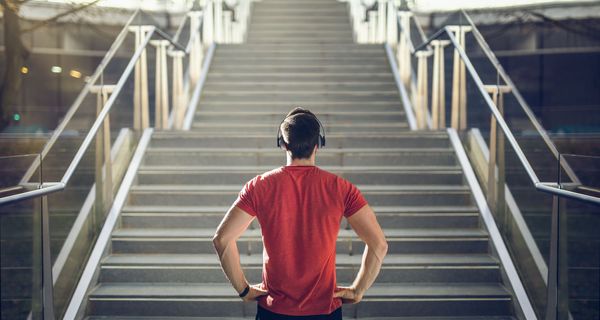 Junger Mann, steht vor einer Treppe.