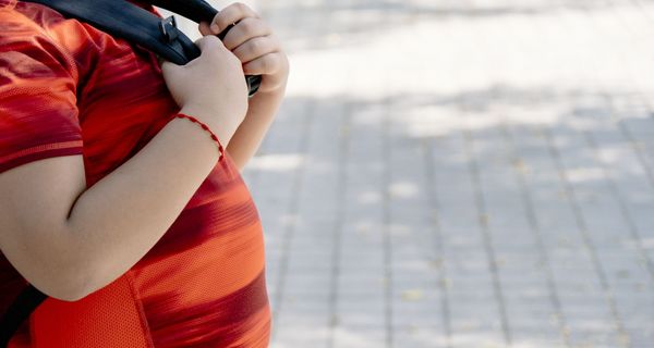 Profil von einem übergewichtigen Jungen mit Rucksack.