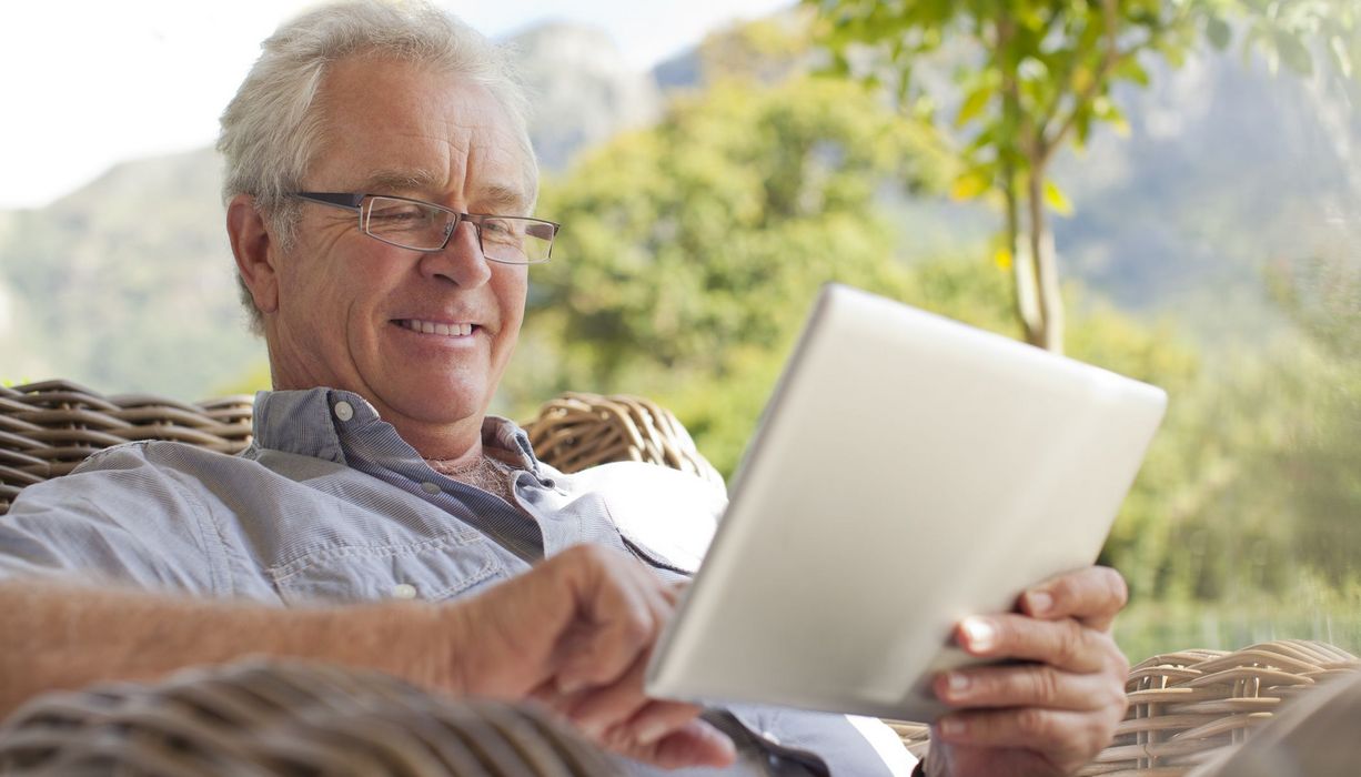 Senior, spielt mit seinem Tablet.