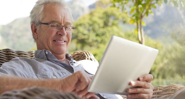 Senior, spielt mit seinem Tablet.