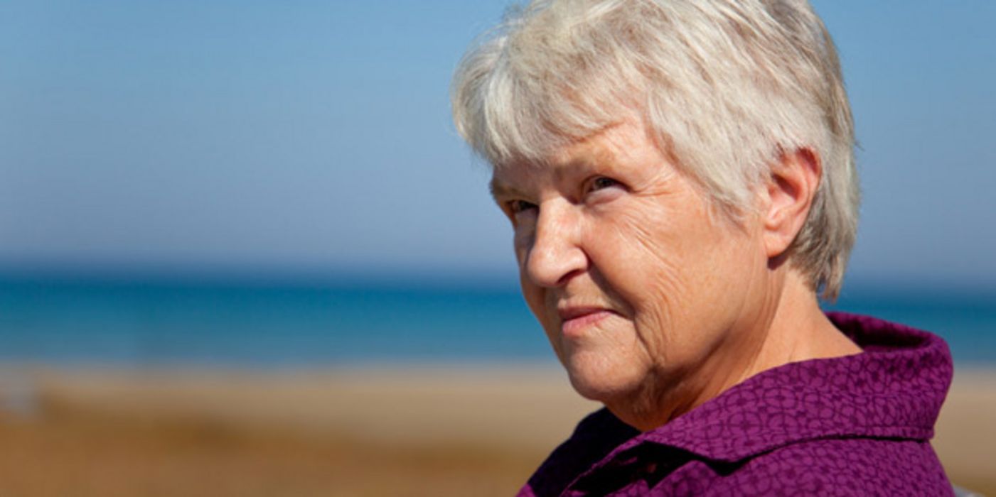 Grauhaarige ältere Frau im Halbprofil schaut traurig