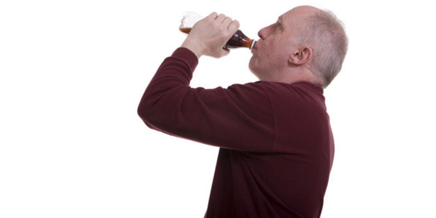 Mann trinkt aus einer kleinen Cola-Flasche