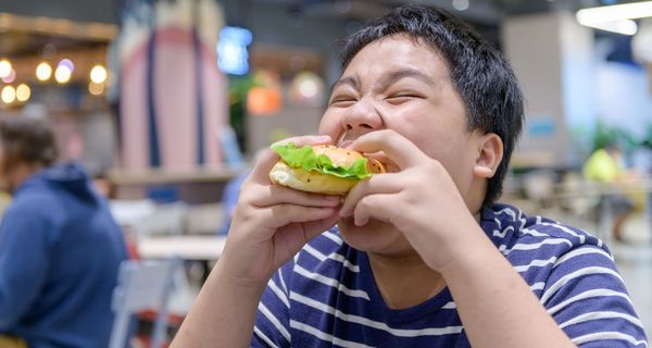 Übergewichtiger Jugendlicher mit Hamburger.