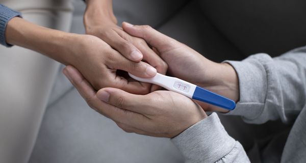 Frau und Mann, halten einen positiven Schwangerschaftstest in der Hand.