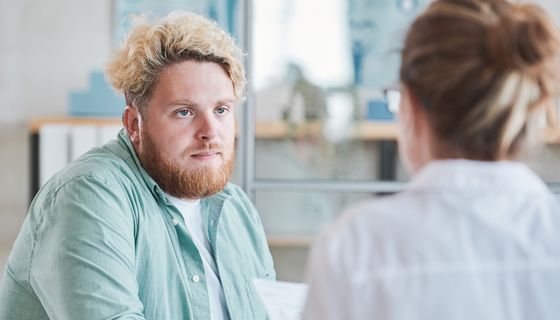 Junger Mann mit Übergewicht im Gespräch mit einer Ärztin.