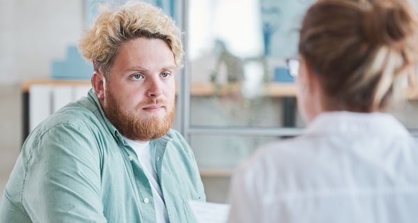 Junger Mann mit Übergewicht im Gespräch mit einer Ärztin.