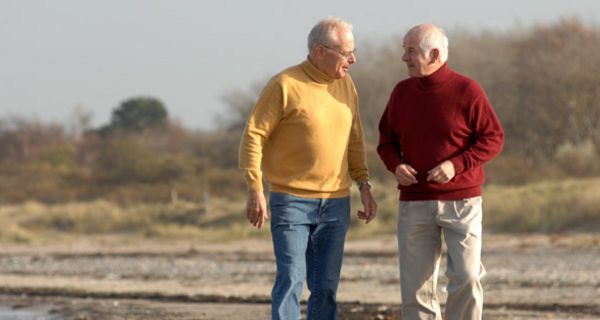 Zwei ältere Männer gehen am Strand spazieren.