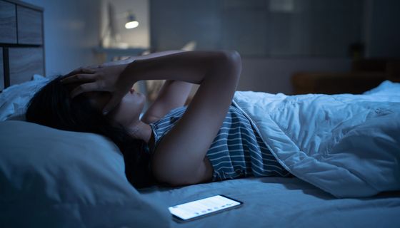 Frau, liegt nachts im Bett und kann nicht schlafen.