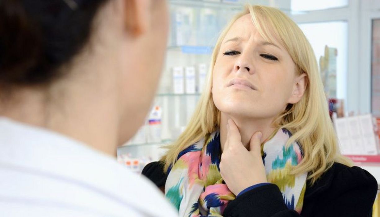 Junge Frau mit Halsschmerzen in der Apotheke