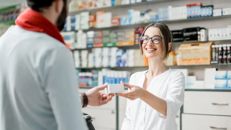 Apothekerin händigt Kunden ein Medikament aus.