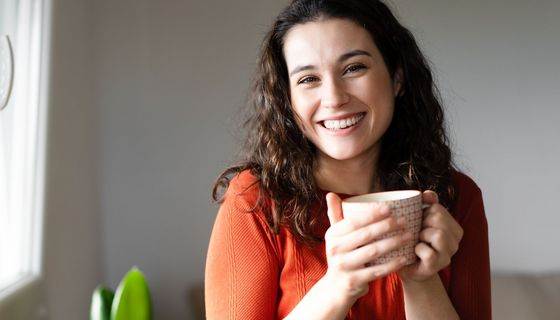 Gut gelaunte Frau trinkt einen Kaffee.