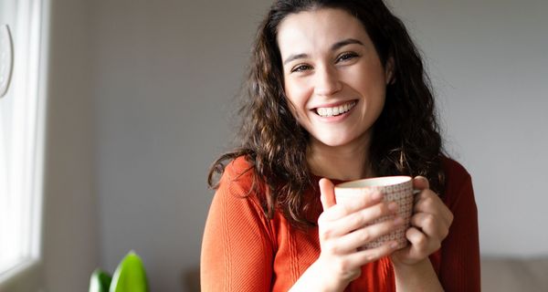 Gut gelaunte Frau trinkt einen Kaffee.